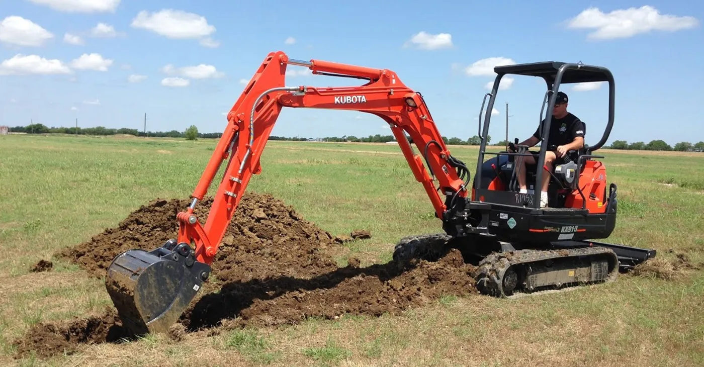 A mini excavator digging on an open lot